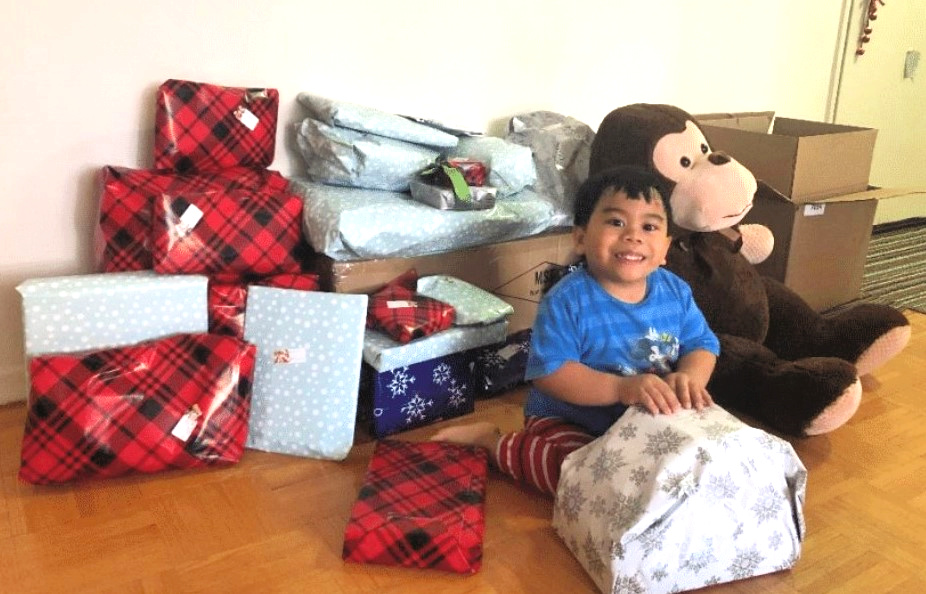 A boy opening his gifts from a Holiday Helpers donation drive