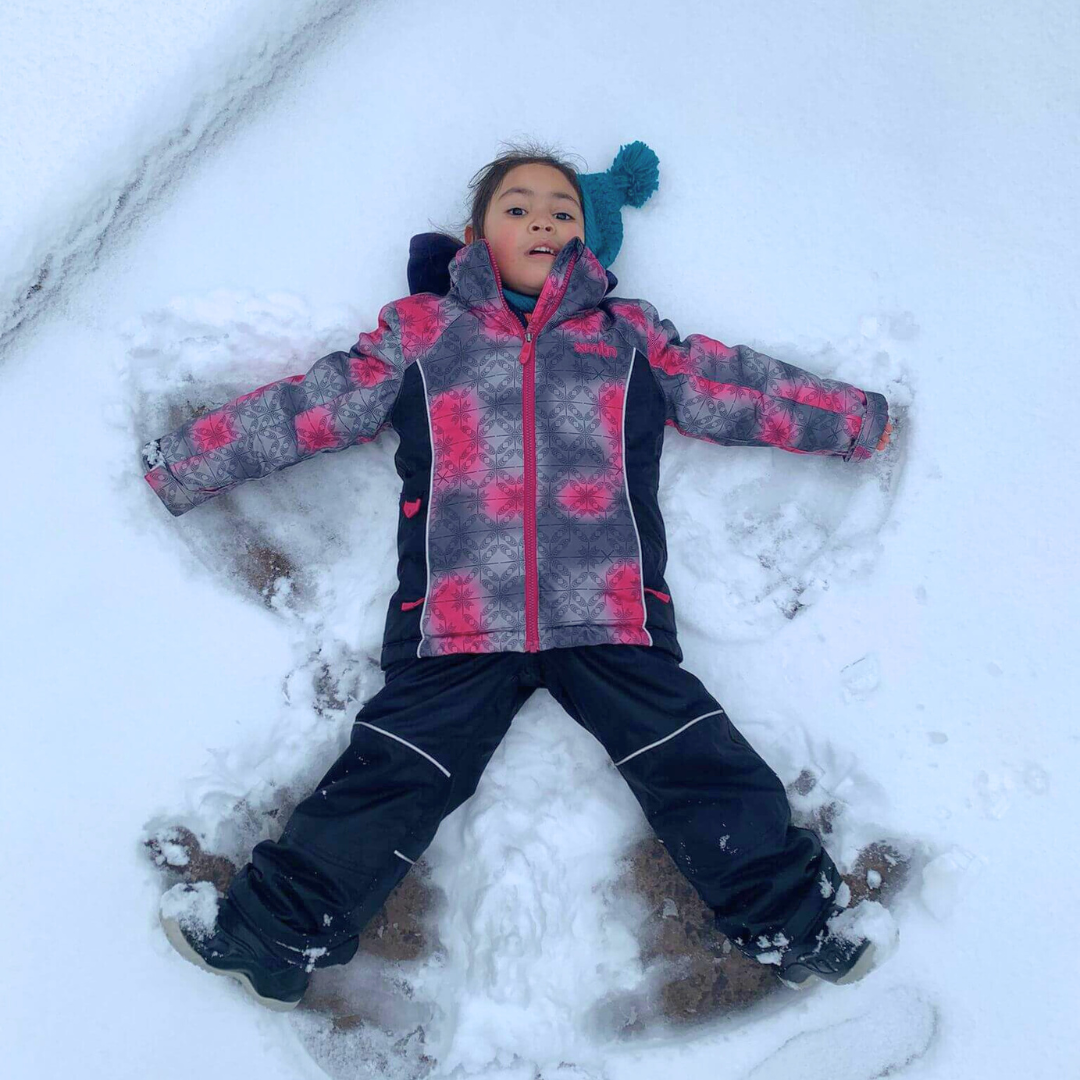 A little girl making snow angels
