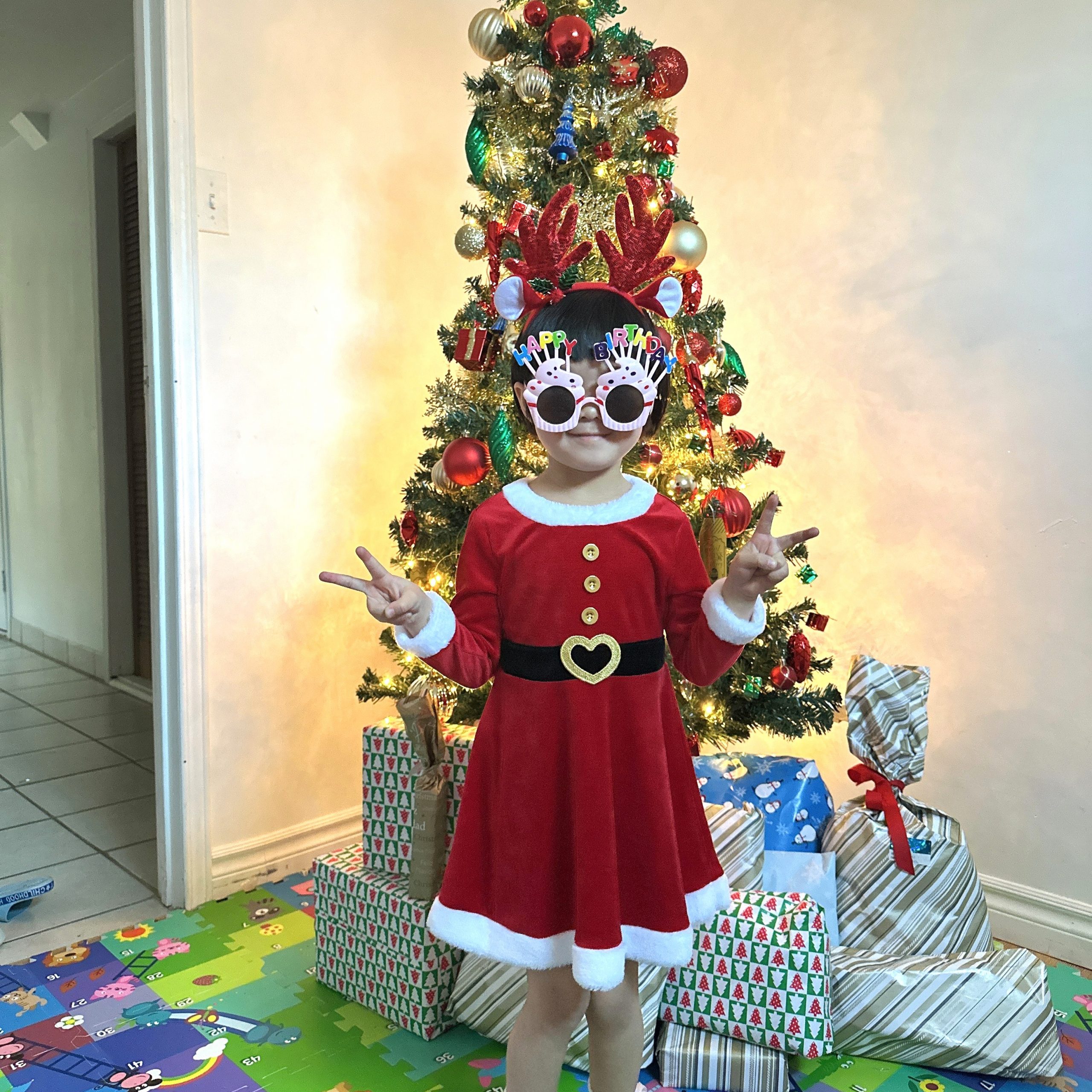 A young girl standing in front of a Christmas Tree